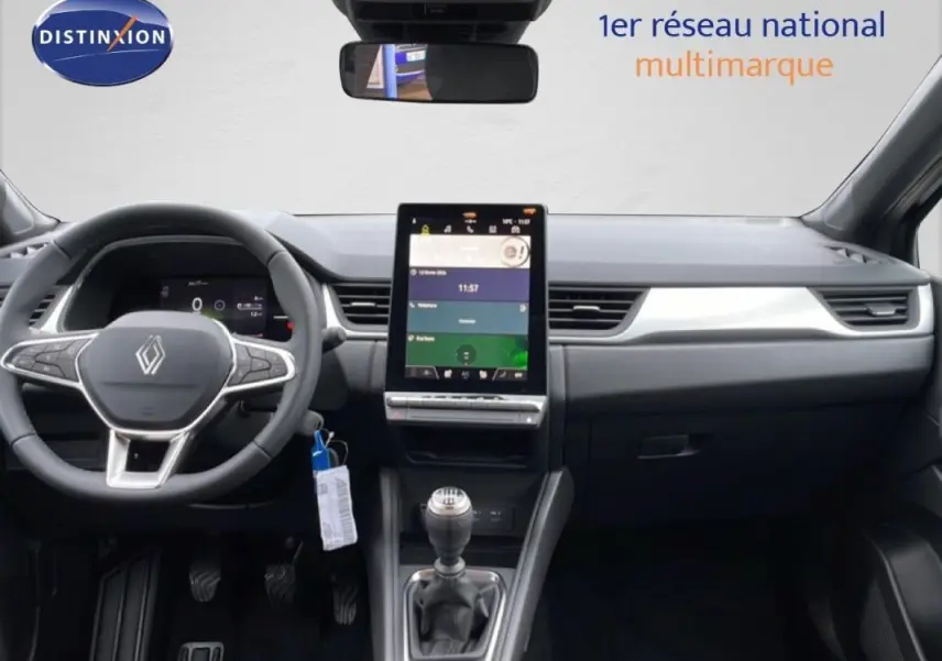 Vue intérieure frontale du tableau de bord noir du Renault Captur 2025 avec écran tactile vertical et volant multifonctions.