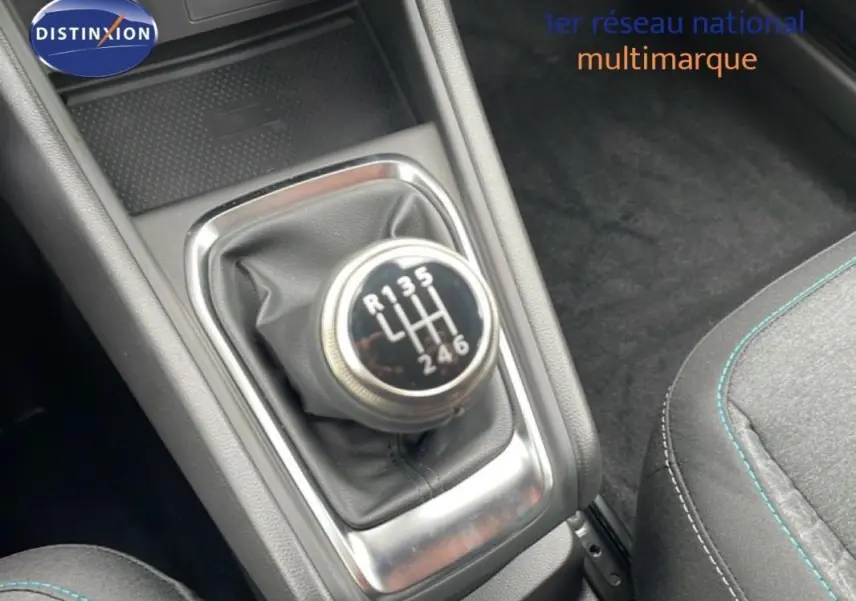 Gros plan sur le levier de vitesses manuel de la Renault Captur noir 2025, avec coutures bleues visibles sur le siège adjacent.