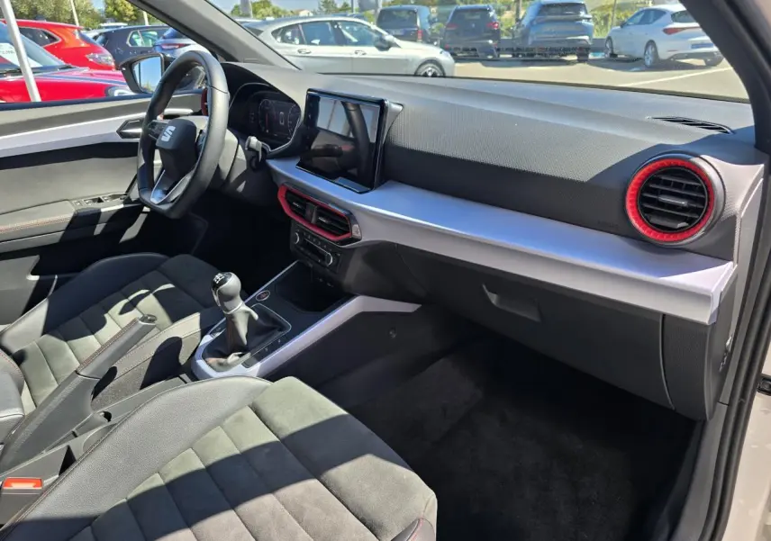 Vue intérieure côté passager du SEAT Arona 2024 avec sellerie suédine noire, volant sport et console centrale moderne.