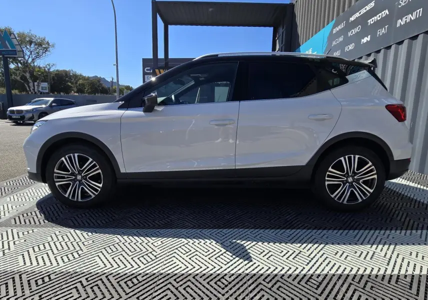 Vue de profil côté gauche du SEAT Arona 2024 blanc avec toit noir et jantes alliage 17 pouces.