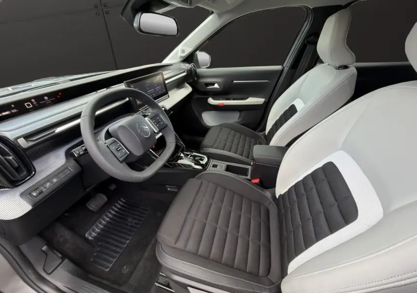 Intérieur avant droit du Citroën C3 Aircross électrique 2025, sièges bicolores noir et gris, tableau de bord moderne avec écran tactile.