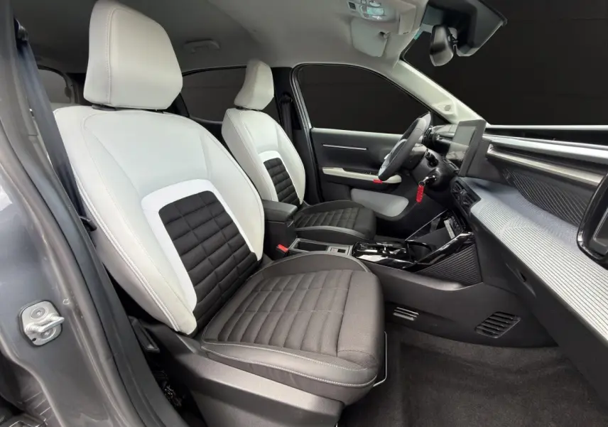 Vue intérieure côté conducteur de la Citroën C3 Aircross électrique 2025, sièges bicolores noirs et blancs, tableau de bord moderne.