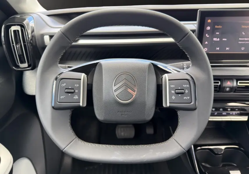 Vue rapprochée du volant cuir noir du Citroën C3 Aircross 2025 avec commandes multifonctions et tableau de bord tactile.