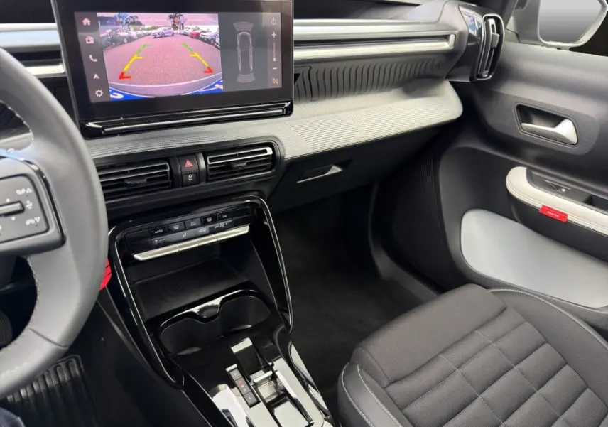 Vue intérieure côté passager du tableau de bord et console centrale noire du Citroën C3 Aircross gris foncé 2025 électrique.