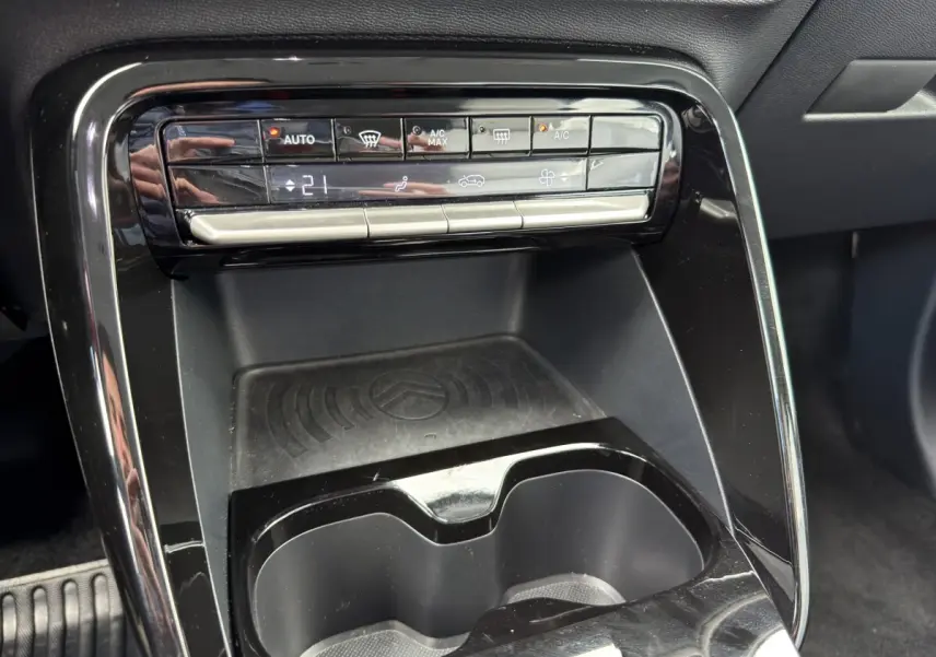 Détail du tableau de bord central noir avec commandes climatisation et zone de recharge sans fil du Citroën C3 Aircross 2025.