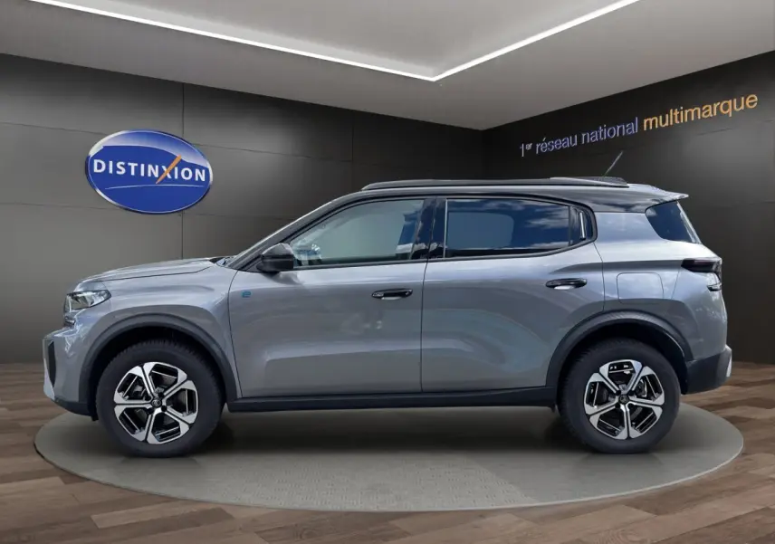 Vue de profil côté gauche d'un Citroën C3 Aircross électrique gris foncé avec jantes distinctives et rails de toit noirs.