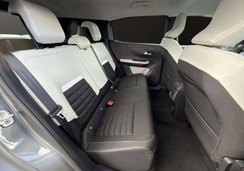 Vue intérieure côté gauche sur la banquette arrière bicolore gris clair et noir du Citroën C3 Aircross électrique gris foncé.