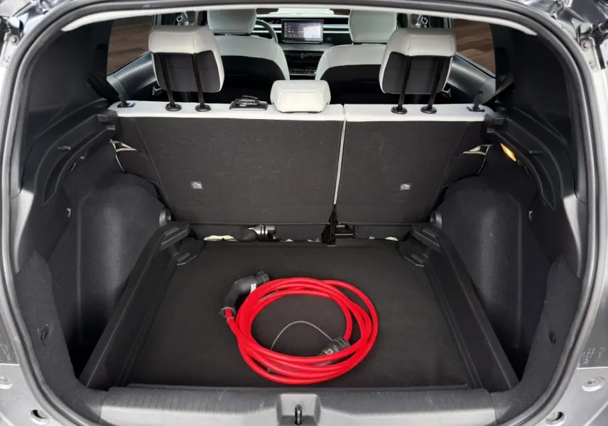 Coffre ouvert d'une Citroën C3 Aircross gris foncé, vue arrière, avec câble de charge électrique rouge visible.