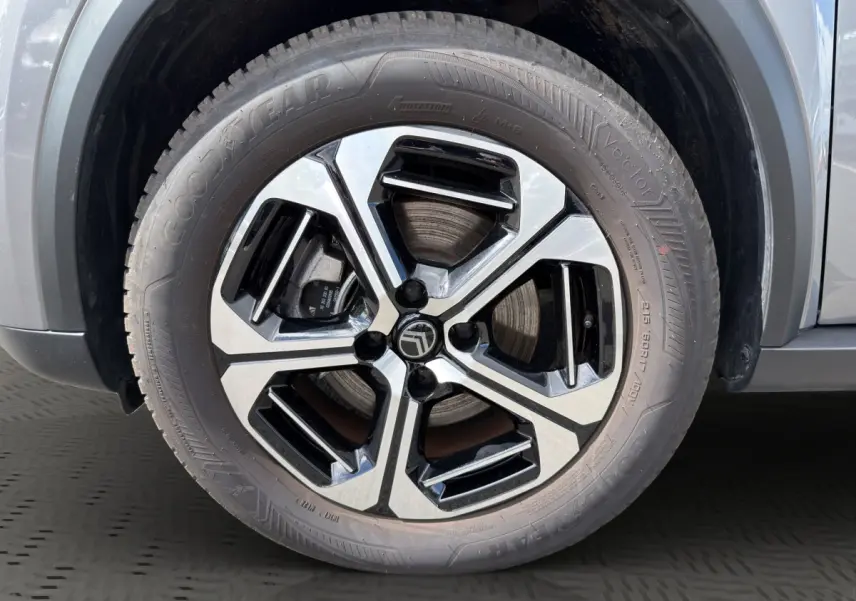 Gros plan sur la roue avant droite du Citroën C3 Aircross électrique gris foncé avec jante alliage bicolore moderne.