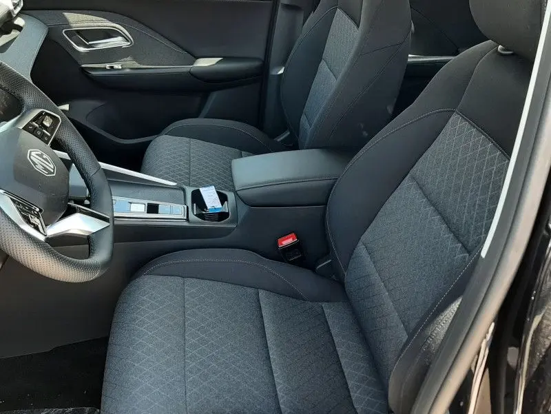 Vue intérieure côté conducteur du MG ZS 1.5 L Hybrid+ 2026 avec sièges tissu gris et console centrale noire.