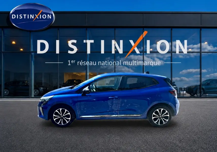 Profil droit d'une Renault Clio V bleu iron garée devant une vitrine avec logo Distinxion.