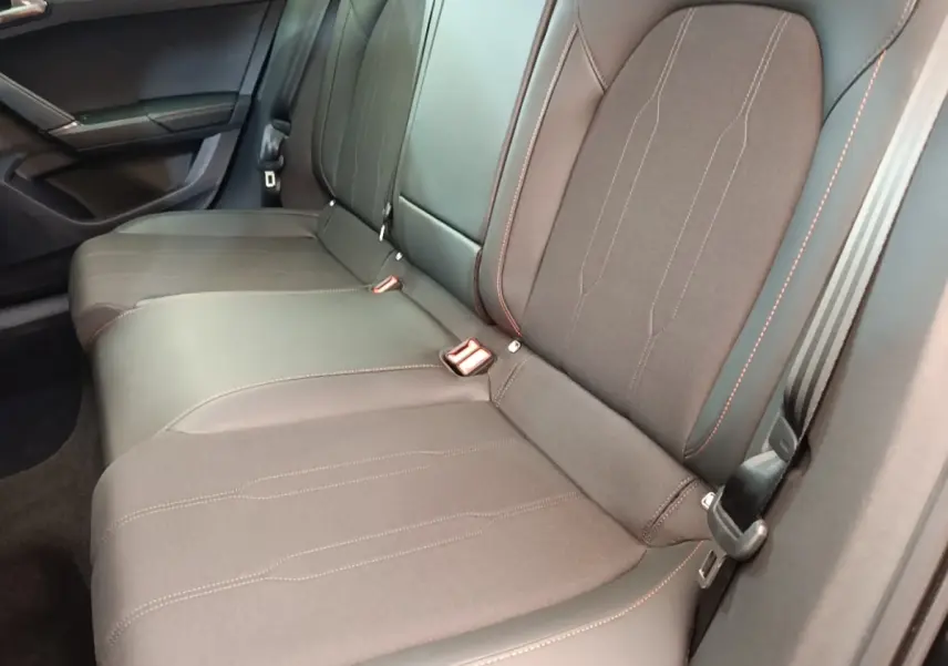 Vue rapprochée de la banquette arrière noire du CUPRA Formentor avec surpiqûres rouges et ceintures de sécurité visibles.