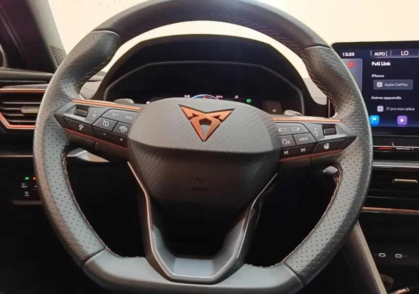 Vue rapprochée du volant en cuir noir perforé du CUPRA Formentor 1.4 e-HYBRID avec commandes intégrées et logo cuivré.
