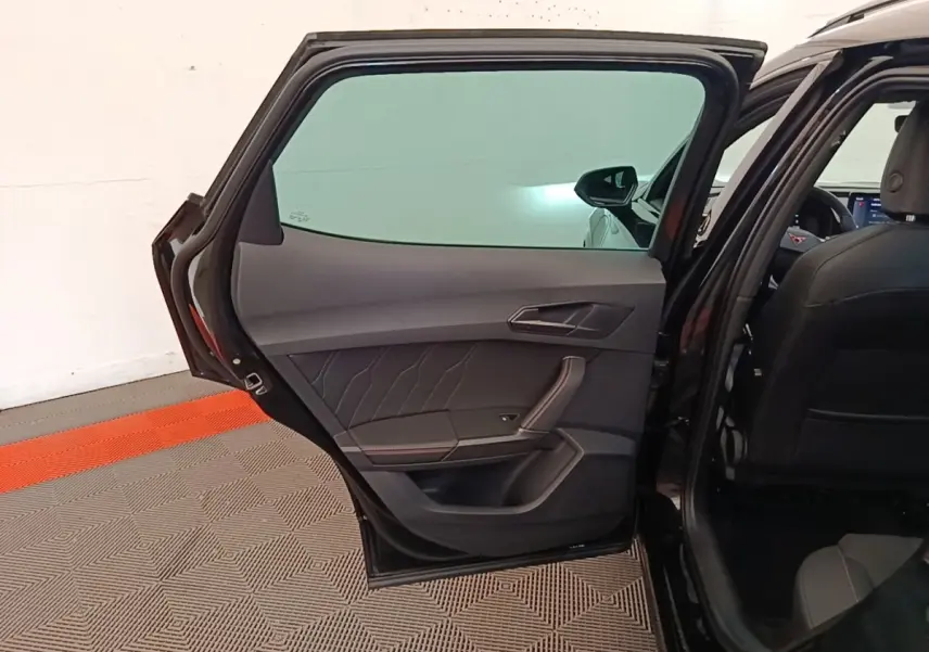 Vue intérieure de la porte arrière gauche ouverte d’un CUPRA Formentor noir, avec sellerie et garnitures sombres.