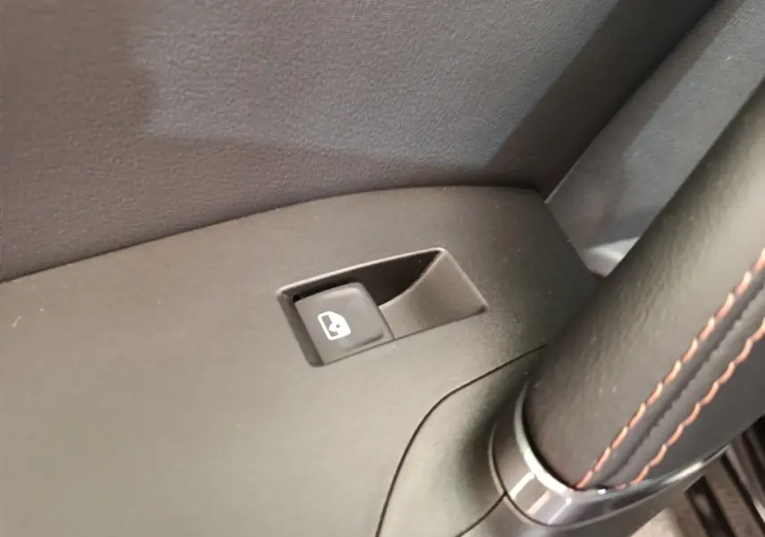 Gros plan sur le bouton de commande de lève-vitre côté conducteur dans l'habitacle noir du CUPRA Formentor 2024.