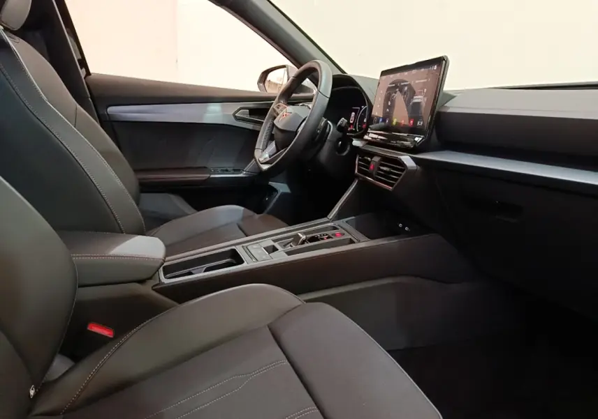 Intérieur noir du CUPRA Formentor 1.4 e-HYBRID 2024, vue côté conducteur avec écran tactile central et volant cuir.