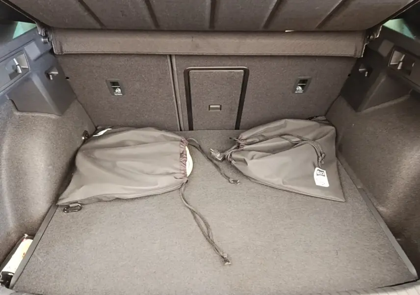 Coffre spacieux du CUPRA Formentor noir 2024, vue intérieure avec tapis gris et deux sacs de rangement noirs.