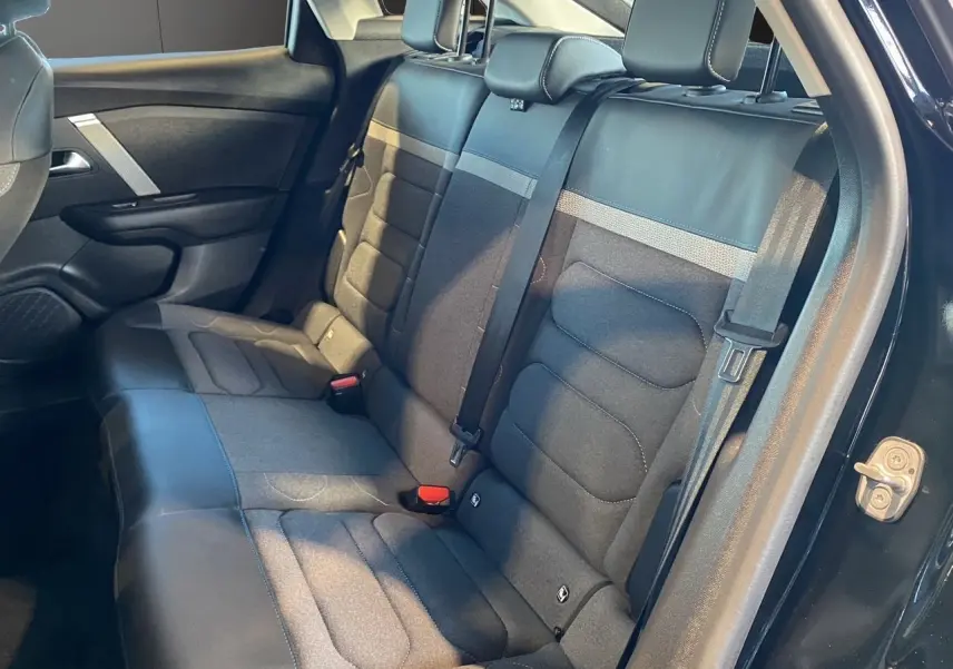 Vue latérale droite de l'intérieur arrière de la Citroën C4 2023 noir Perla Nera avec sièges en tissu et cuir gris noir.