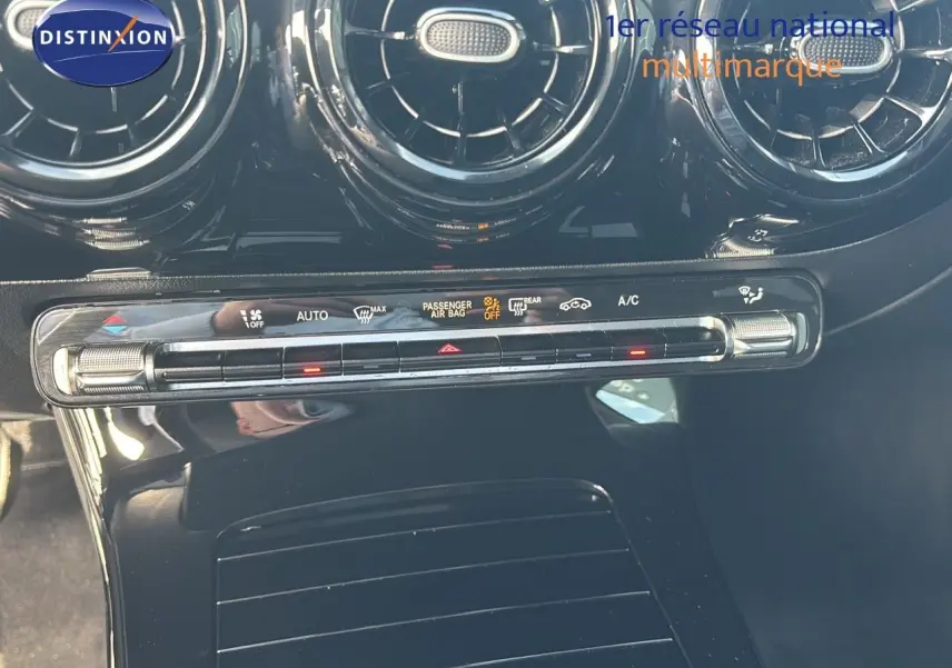 Vue rapprochée de la console centrale noire brillante avec commandes climatisation et aérateurs ronds d’une Mercedes Classe A 200D.
