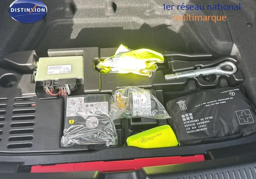 Coffre ouvert d'une Mercedes Classe A 200D gris montagne métal, montrant le kit de secours et outils rangés.