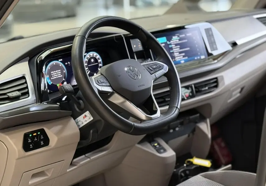 Vue intérieure côté conducteur du tableau de bord beige et volant cuir multifonction du Volkswagen California T7 2024.