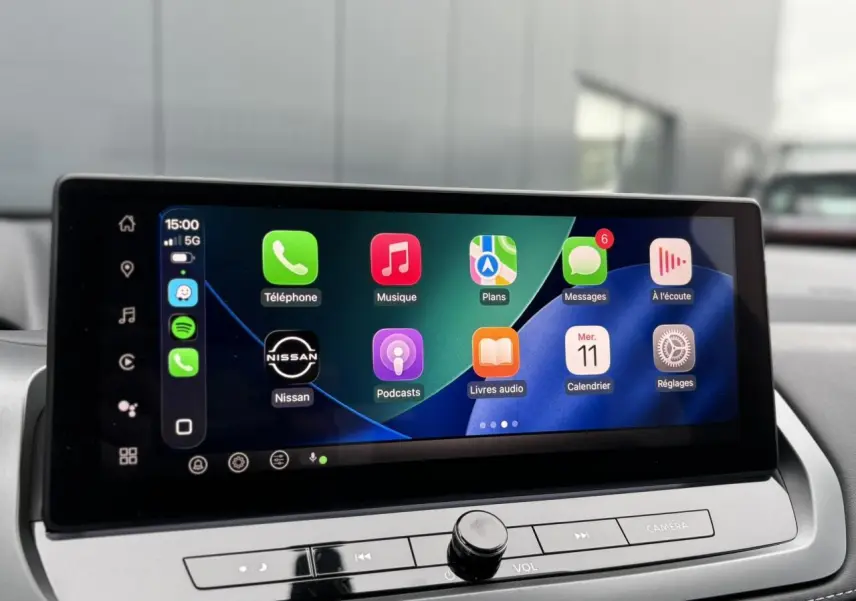 Écran tactile central affichant Apple CarPlay dans l'habitacle du Nissan Qashqai gris, vue de face rapprochée.