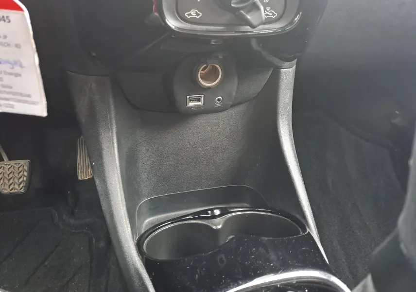 Vue rapprochée de la console centrale noire du Peugeot 108 bleu, avec prise USB, allume-cigare et porte-gobelets.