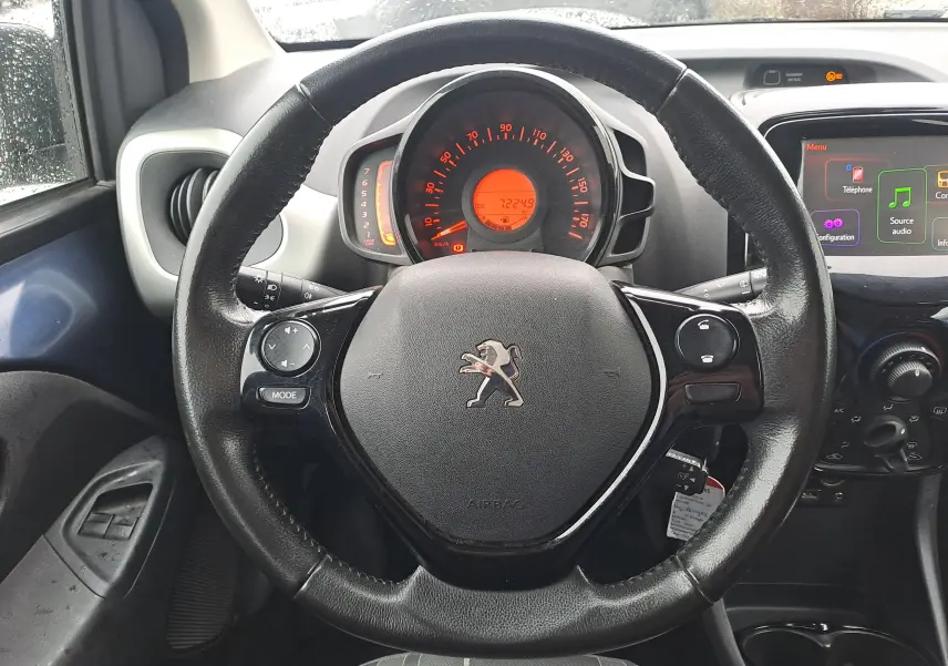Vue intérieure centrée sur le volant noir de la Peugeot 108 avec tableau de bord et écran tactile visibles.
