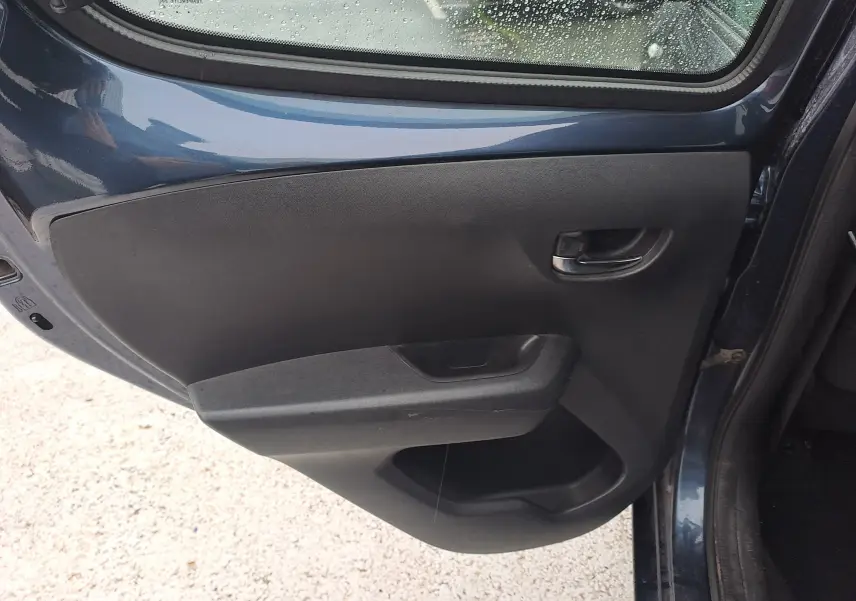 Vue intérieure de la porte arrière gauche d'une Peugeot 108 bleu 2016, avec poignée et panneau noir simple.