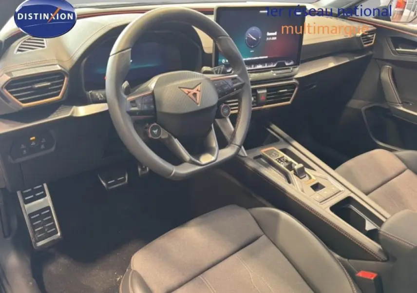 Intérieur de la CUPRA Leon ST 2025 vu côté conducteur, volant cuir avec logo, écran tactile et console centrale moderne.