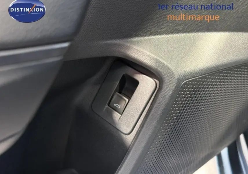 Détail du bouton d'ouverture de coffre sur la porte intérieure côté gauche d'une CUPRA Leon gris 2025.