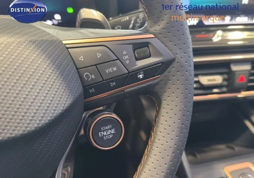 Gros plan sur le volant cuir perforé gris avec commandes intégrées et bouton start/stop du CUPRA Leon ST 2025.