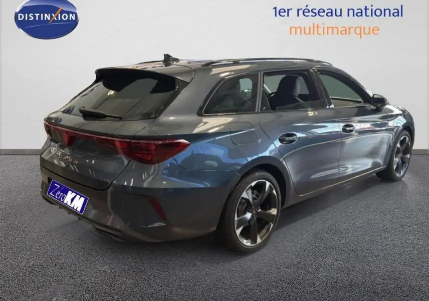 Vue 3/4 arrière droite d'une CUPRA Leon ST gris métallisé avec barres de toit et jantes aluminium.