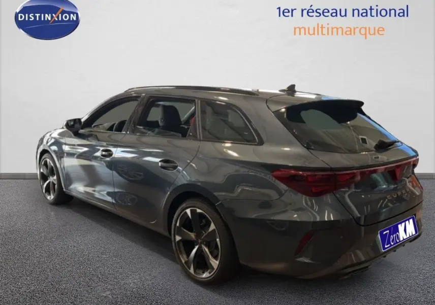 Vue 3/4 arrière côté droit d'une CUPRA Leon ST gris métallisé avec barres de toit et jantes aluminium.