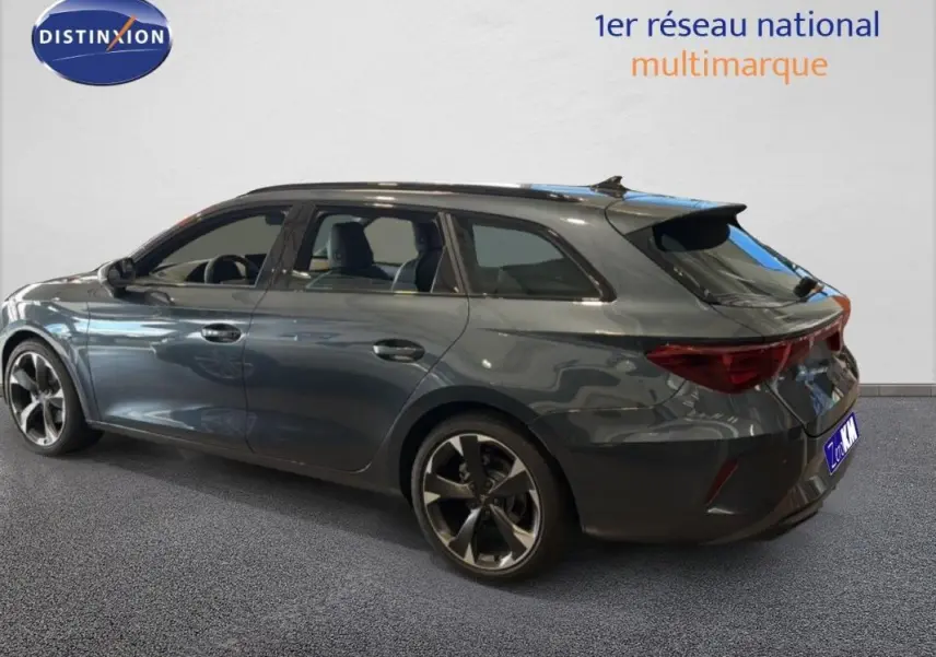 Vue 3/4 arrière droite d'une CUPRA Leon ST gris métallisé avec barres de toit et jantes aluminium distinctives.