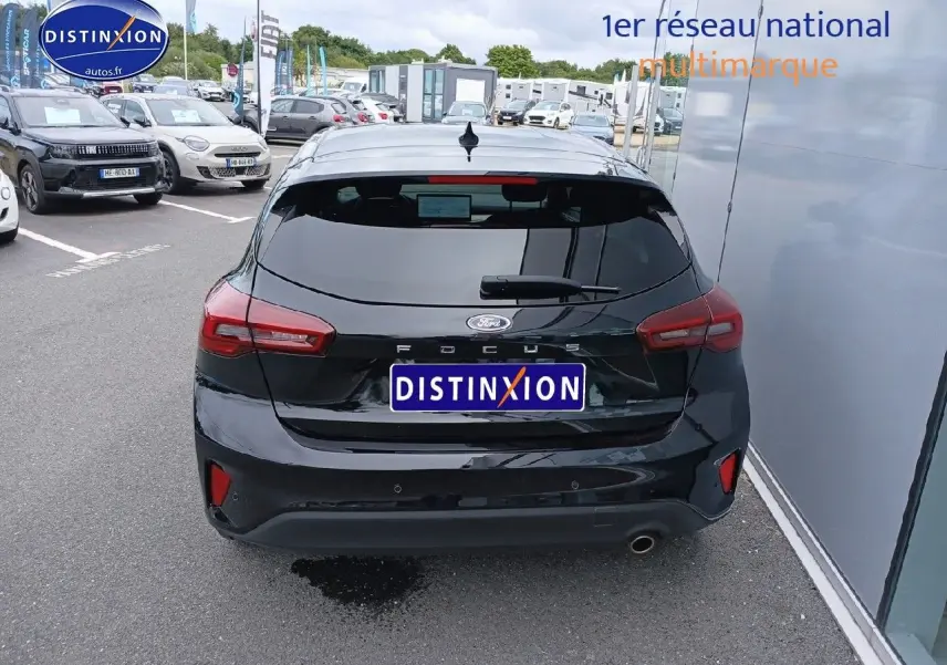 Vue arrière d'une Ford Focus 2024 noir Agate métallisé, avec feux arrière LED et sortie d'échappement chromée visible.