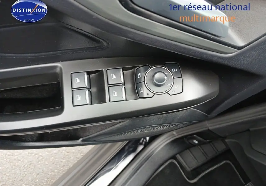 Vue rapprochée des commandes de lève-vitres et rétroviseurs sur la porte côté conducteur d’une Ford Focus noir Agate 2024.