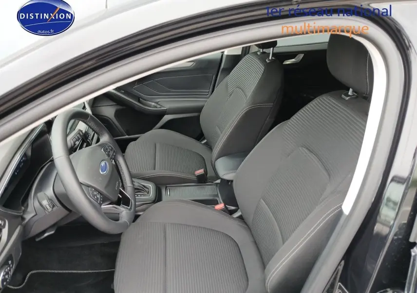Vue intérieure côté conducteur de la Ford Focus 2024 noir Agate, montrant sièges tissu et volant multifonction cuir.