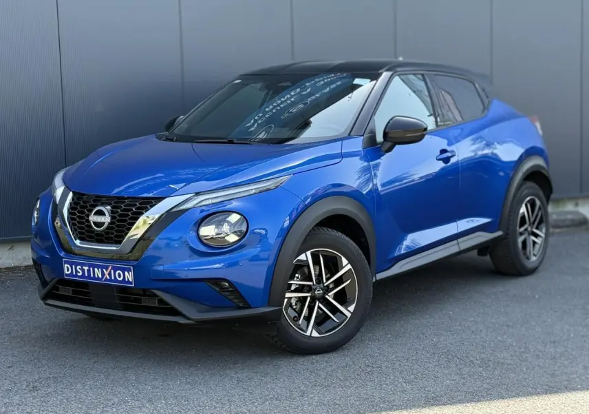 Vue 3/4 avant droite du Nissan Juke 2025 bleu magnétique avec toit noir et jantes alliage 17 pouces diamantées.