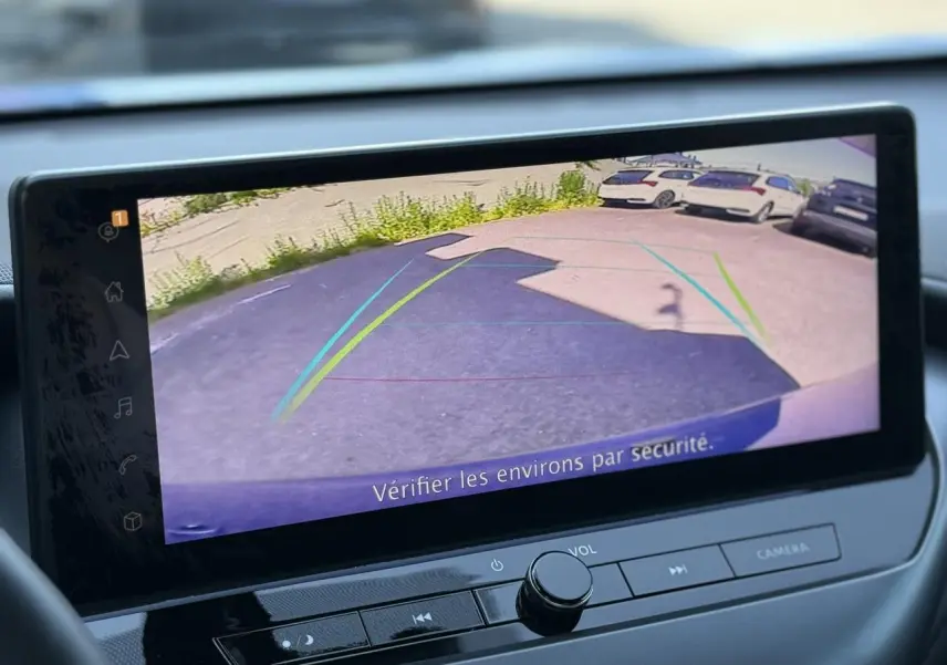 Écran tactile intérieur du Nissan Juke 2025 montrant la caméra de recul avec lignes d’aide au stationnement.