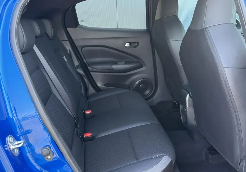 Vue intérieure arrière côté gauche du Nissan Juke 2025 bleu magnétique avec banquette tissu noir et ceintures grises.
