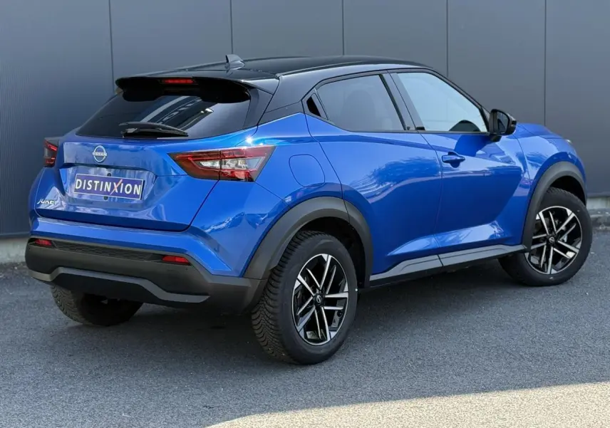Nissan Juke 2025 bleu magnétique et toit noir, vue 3/4 arrière côté gauche avec jantes alliage 17 pouces.