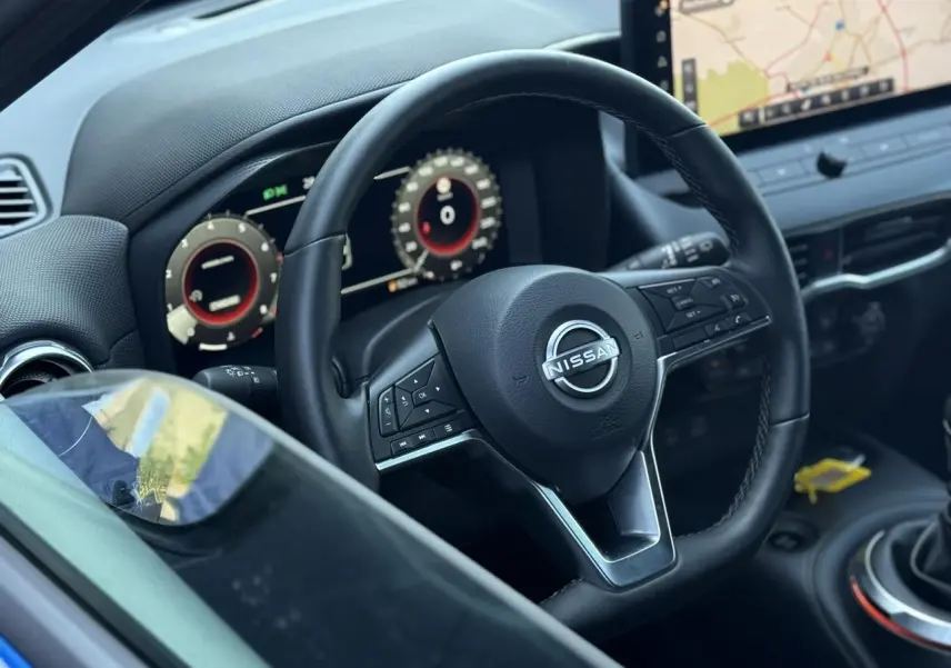 Vue rapprochée du volant noir et du tableau de bord digital du Nissan Juke 2025 avec écran tactile et commandes intégrées.