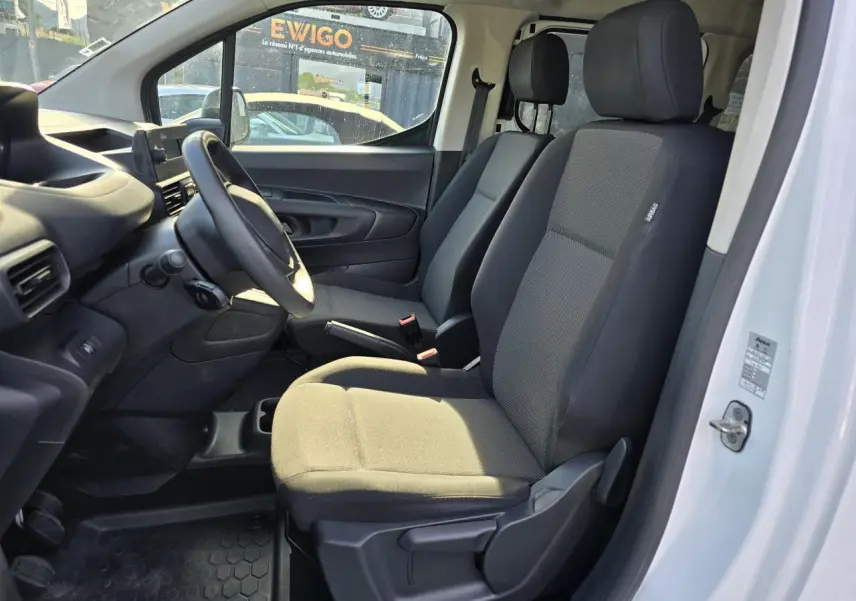 Vue intérieure côté conducteur du Peugeot Rifter blanc Banquise 2021, sièges tissu gris et tableau de bord noir.