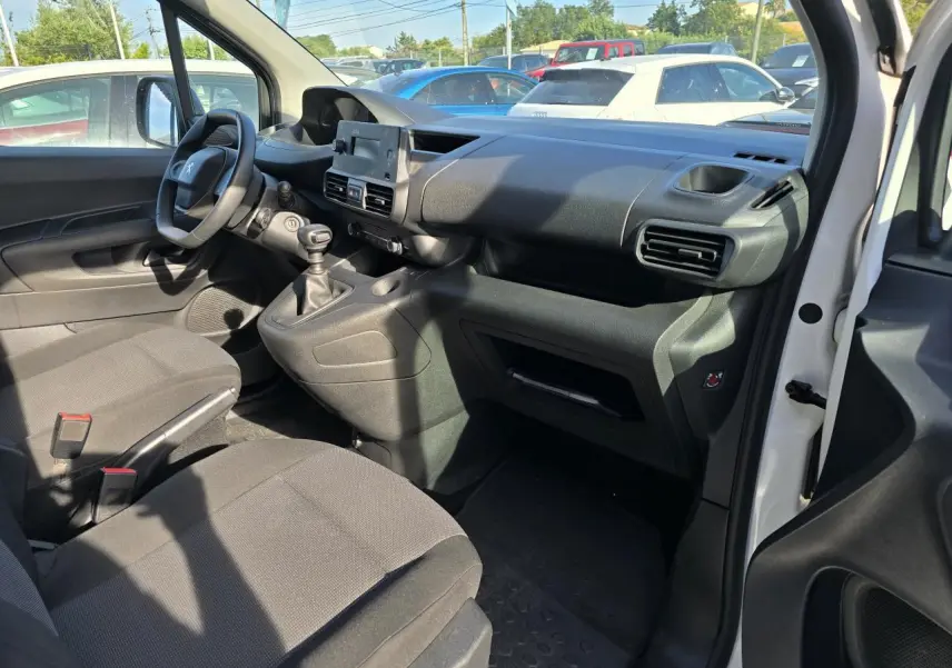 Vue intérieure côté conducteur du Peugeot Rifter blanc Banquise 2021, montrant le tableau de bord et la boîte manuelle.