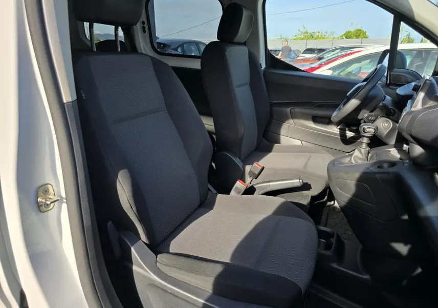 Vue intérieure côté conducteur du Peugeot Rifter 1.5 BlueHDi 100, montrant les sièges tissu gris et la boîte manuelle.