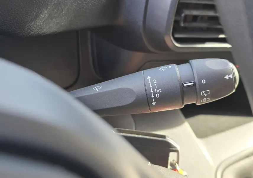 Gros plan sur la commande d’essuie-glace noire à gauche du volant dans l’habitacle du Peugeot Rifter blanc Banquise.