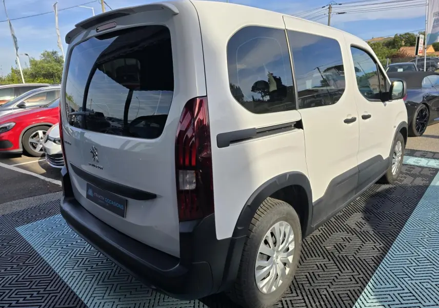 Vue 3/4 arrière droite du Peugeot Rifter blanc Banquise avec vitres teintées et protections noires sur pare-chocs et bas de caisse.