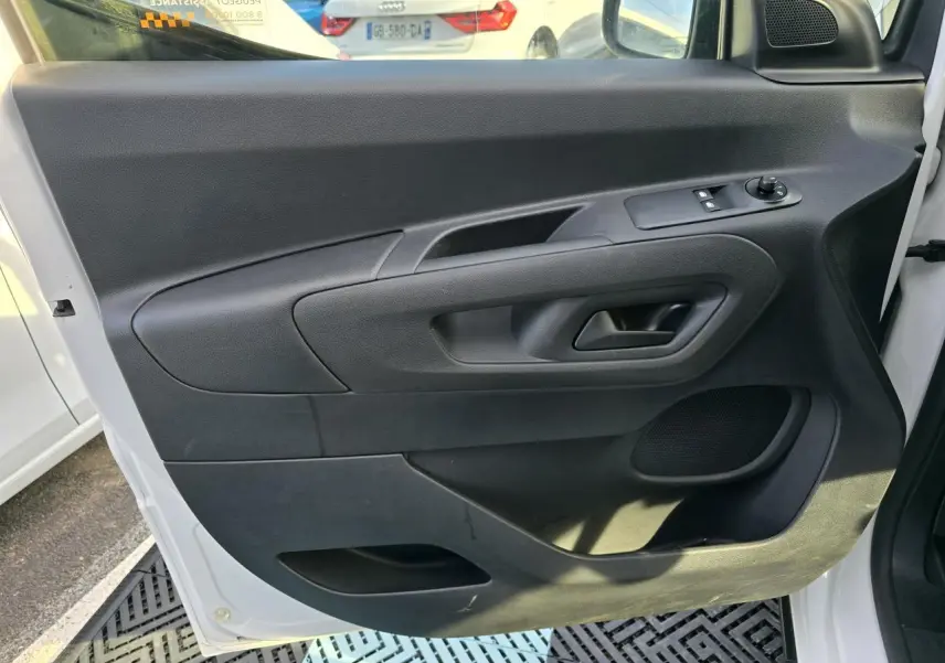 Vue intérieure de la porte avant gauche noire du Peugeot Rifter blanc Banquise 2021 avec commandes électriques et haut-parleur intégré.