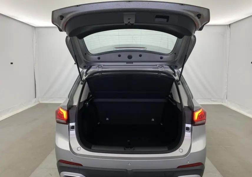 Vue arrière du MG ZS 1.5 L Hybrid+ 2026 en Cosmic Silver avec coffre ouvert et feux arrière allumés.